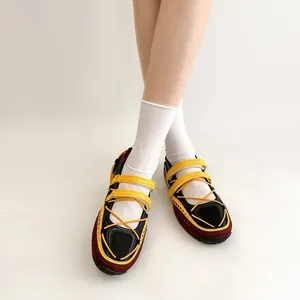 Close-up of functional Mary Jane sneakers with yellow straps and white socks.