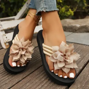 Detalle de chanclas planas de mujer con una gran flor decorativa de tela beige