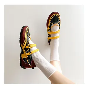 Detail shot of sporty burgundy and yellow Mary Jane sneakers worn with white socks.