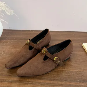 Dettaglio di scarpe Mary Jane a punta in camoscio marrone con elegante fibbia a rosa d'oro