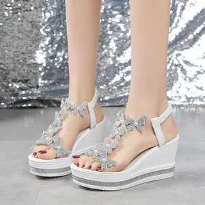 Close-up of white wedge sandals with butterfly pearl decorations and rhinestone details