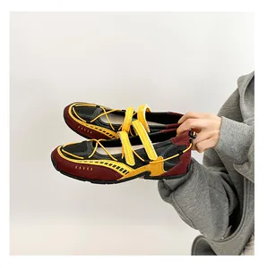 Close-up of functional ballet Mary Jane sneakers in burgundy and yellow held by hand