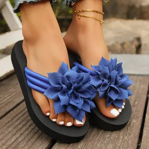 Primer plano de elegantes chanclas con flores de tela azul en los pies al aire libre.