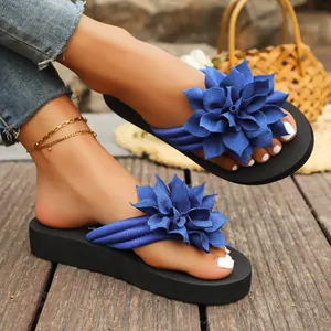 Primer plano de chanclas con flores azules para mujer en tarima de madera