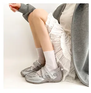 Side view of silver functional ballet sneakers styled with white socks and ruffled skirt