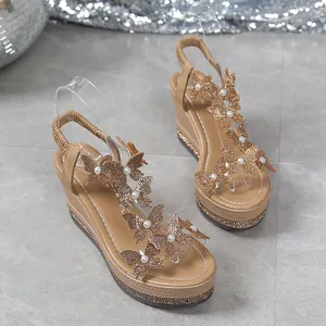 Detail of golden wedge sandals featuring delicate butterfly and pearl decorations