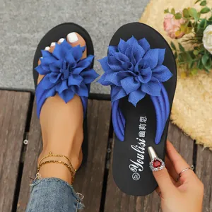 Detalle de chanclas planas para mujer con una gran flor de tela azul muy decorativa