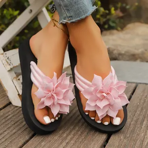 Detalle de chanclas con plataforma negras para mujer con grandes flores decorativas de tela rosa