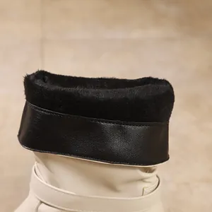 Close-up of black faux fur lining on stylish cream-colored pointed-toe ankle boots.