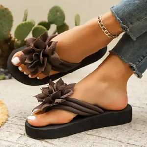 Vista detallada de chanclas para mujer con un gran adorno de flor de tela marrón.