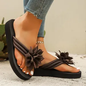 Detalle de chanclas de mujer con flores decorativas marrones y suelas de plataforma.