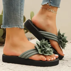 Primer plano de chanclas con plataforma para mujer con elegante flor verde decorativa