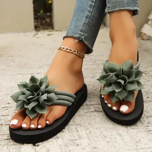 Vista detallada de chanclas planas para mujer con grandes flores decorativas de tela verde