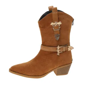 Macro detail of brown suede western boot featuring gold bat buckles and pointed toe.