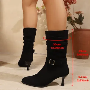 Detailed view of black pointed-toe boots with kitten heels and metallic buckle strap