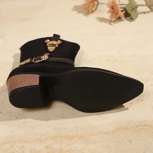 Close-up detail of black Western ankle boot featuring gold buckle and textured sole