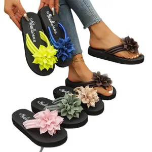 Chanclas planas de mujer con grandes decoraciones de flores de tela de colores.