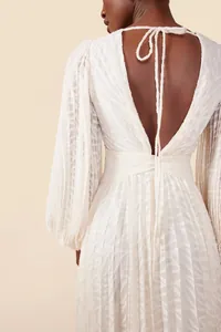 Back detail of elegant white pleated jacquard dress with lantern sleeves and tie