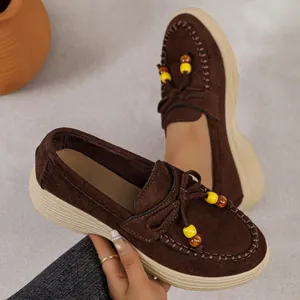 Gedetailleerd overzicht van bruine suède platform loafers voor dames met kralenaccenten
