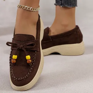 Detailopname van bruine suède loafers met decoratieve kralen en dikke platformzolen