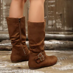 Close-up of brown slouchy mid-calf boots with buckle details on a model