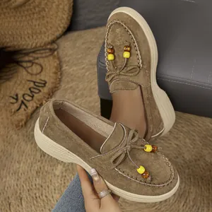 Detail van bruine suède platform loafers met kralenbedels en mocassin stiksels.
