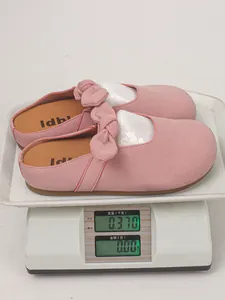 Pink suede bow platform mules on weighing scale showing product weight detail