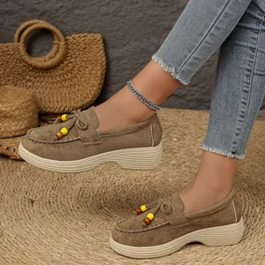 Detail van bruine suède platform loafers met kralen kwastjes en dikke zool