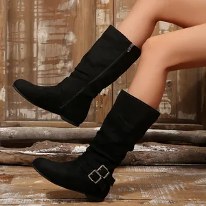 Detail view of stylish black slouch mid-calf boots with buckle detail on a model