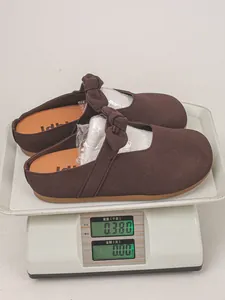 Detail view of brown suede mule clog with bow strap showing product weight on scale