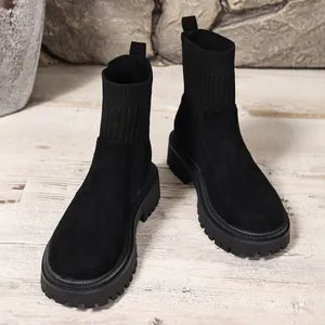 Primer plano de botines negros con suela gruesa para mujer sobre suelo madera