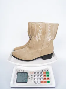 Detail shot of lightweight beige embroidered western boots being weighed on a scale.