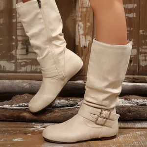Detailed side view of cream slouchy high-top boots with decorative ankle buckles
