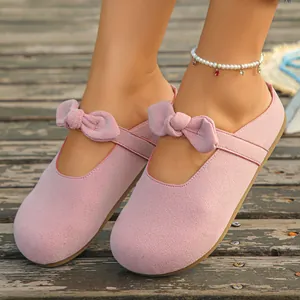 Detailed view of stylish pink suede-like mule sandals featuring a charming bow decoration