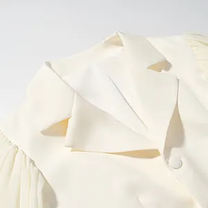 Detail view of cream blazer with notched lapel and pleated puff sleeves.