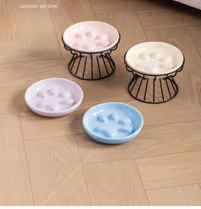 Detail view of colorful ceramic paw-shaped slow feeder pet bowls with black stands.