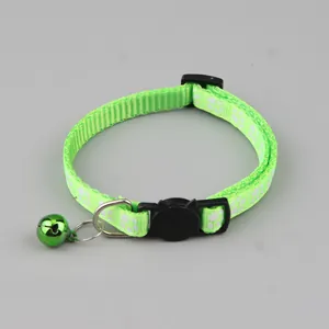 Detailopname van een lichtgroene kattenhalsband met witte pootafdrukken en groen belletje
