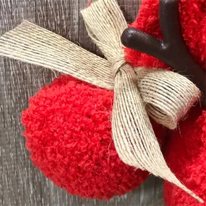Close-up of red plush texture with a hemp rope bow on a faceless Christmas doll.