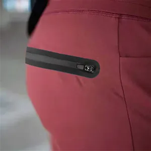 Close-up detail of the black waterproof zipper pocket on men's burgundy athletic pants