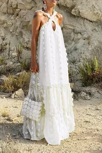 Detailed view of the 3D floral appliques on a white floor-length halter maxi dress