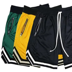 Dettaglio dei pantaloncini da basket in mesh traspirante in verde, giallo e nero con cerniere