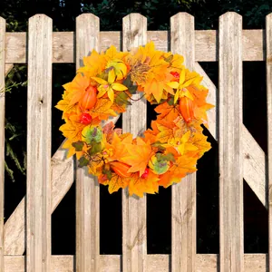 Handcrafted autumn maple leaf wreath with pumpkins and yellow flowers on wooden fence
