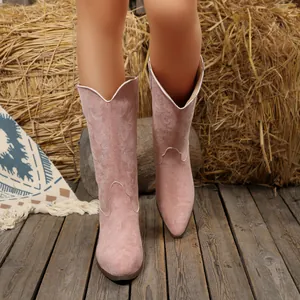 Vista dettagliata di stivali da cowboy in camoscio rosa con ricami bianchi intricati