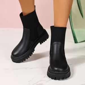 Primer plano de botines tipo calcetín de punto negro con suela de tractor en una modelo.