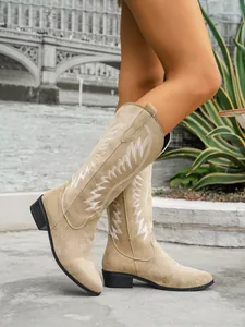 Detail view of beige suede western tall boots with white embroidery and block heel.