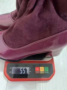 Detailed view of a burgundy patchwork boot on a digital scale showing 557 grams