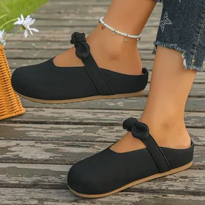 Detail shot of black bow-knot fabric Mary Jane mules on a rustic wooden walkway