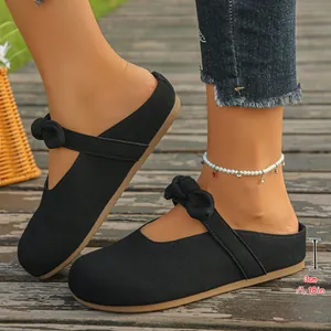 Close-up of black bow-tie Mary Jane mules showing 3cm platform heel on a wooden deck