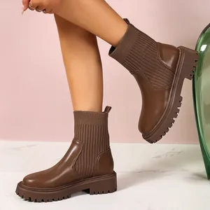 Imagen detallada de botines marrones con suela gruesa y parte superior de punto acanalado.