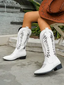 Detailed side view of white Western tall boots with black embroidery and chunky heel